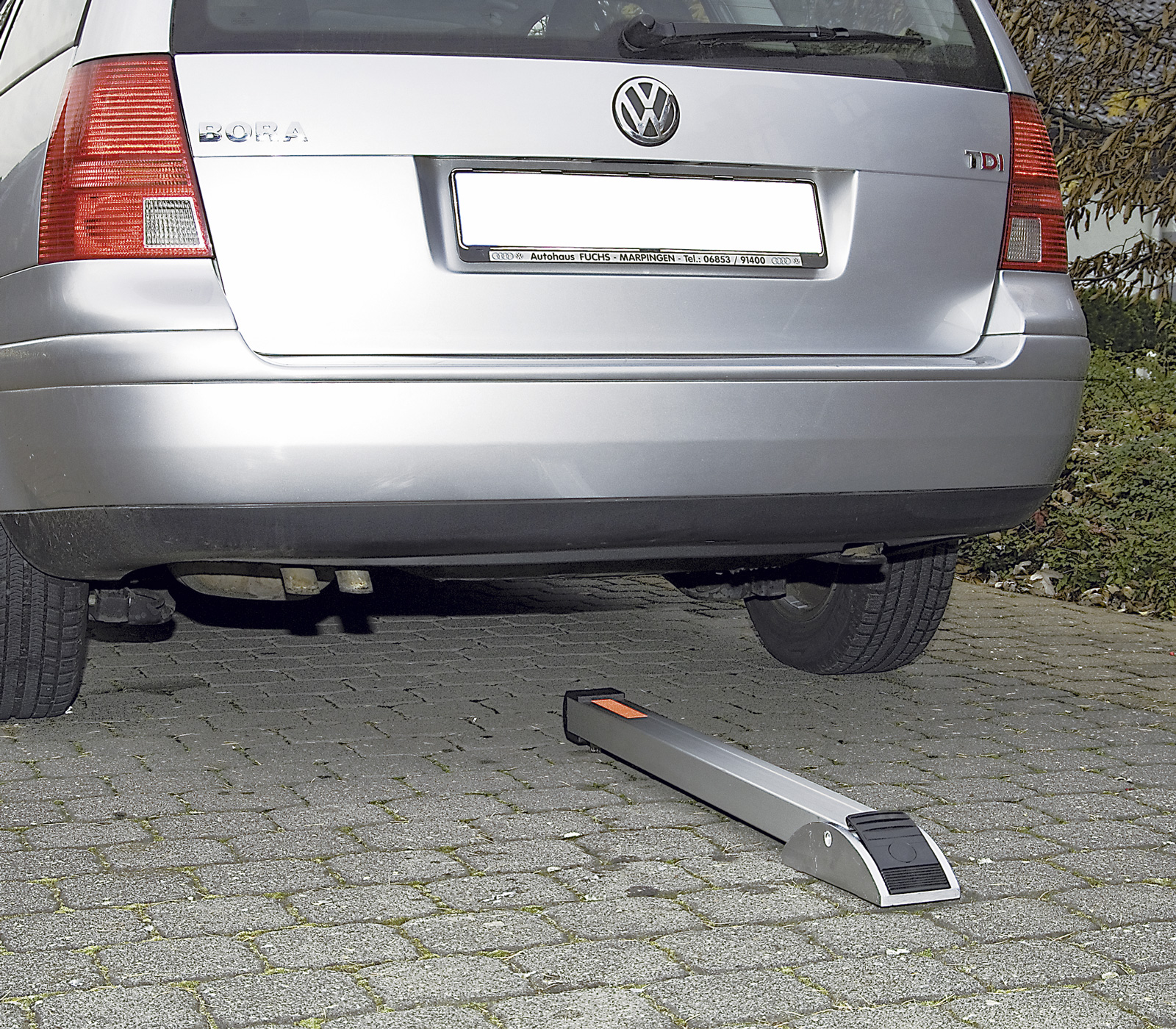 Umlegbarer Pfosten mit Schliessung unter Auto auf Parkplatz