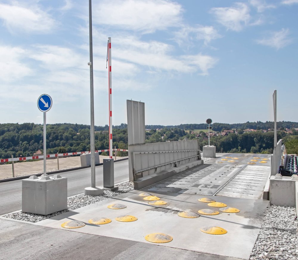 Fahrbahnschwellen und Schrankenanlage sichern die Einfahrt